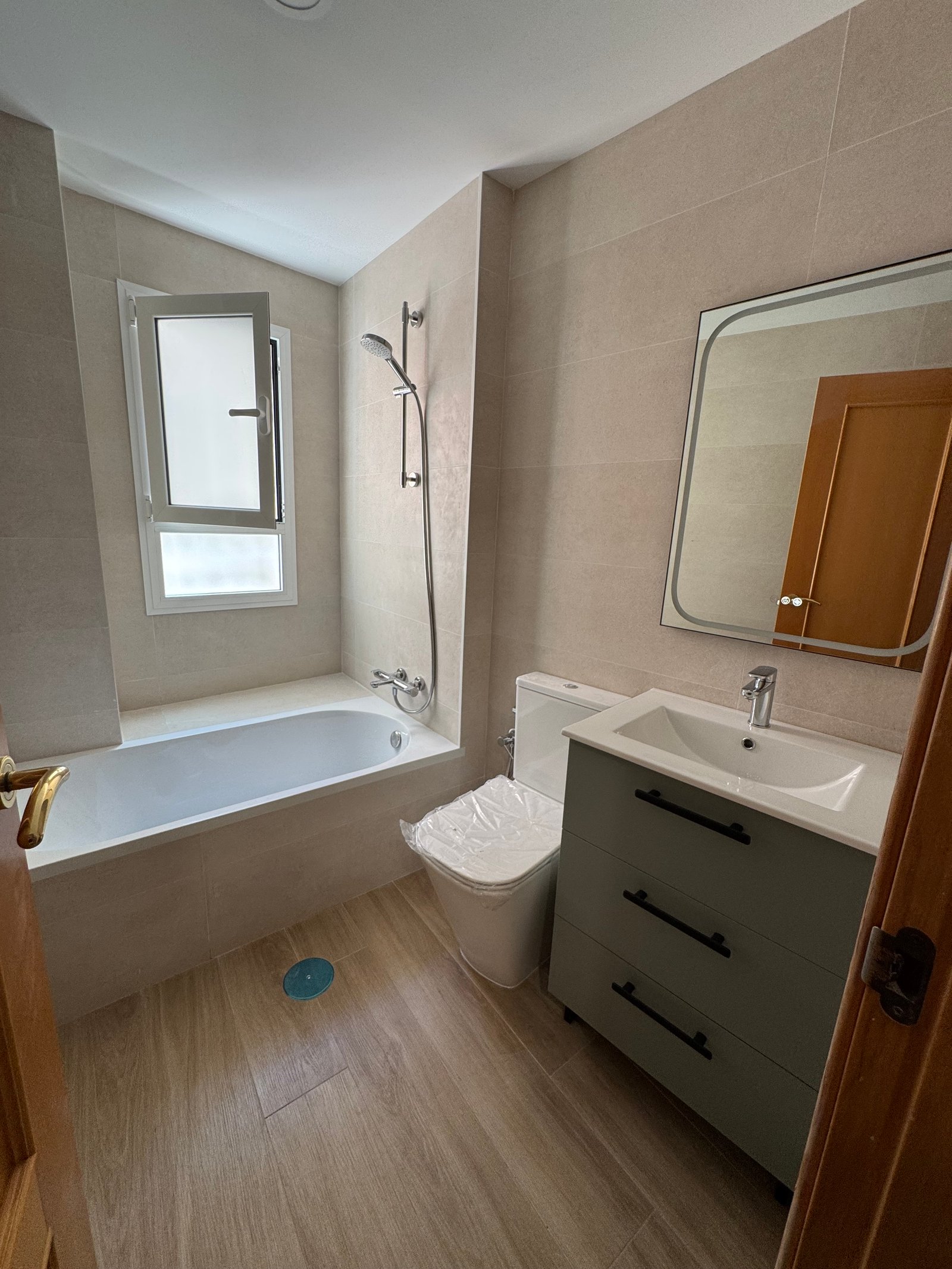 Baño con bañera, mueble de espejo y grifería en una reforma en Sevilla